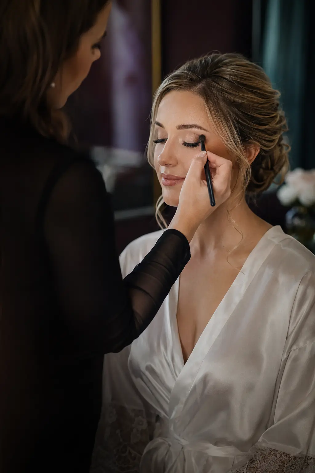 A professional makeup artist applying elegant wedding makeup to a bride